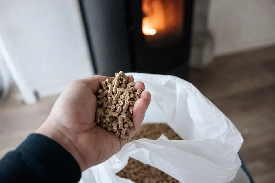 Main tenant une poignée de granulés de bois au-dessus d'un sac ouvert