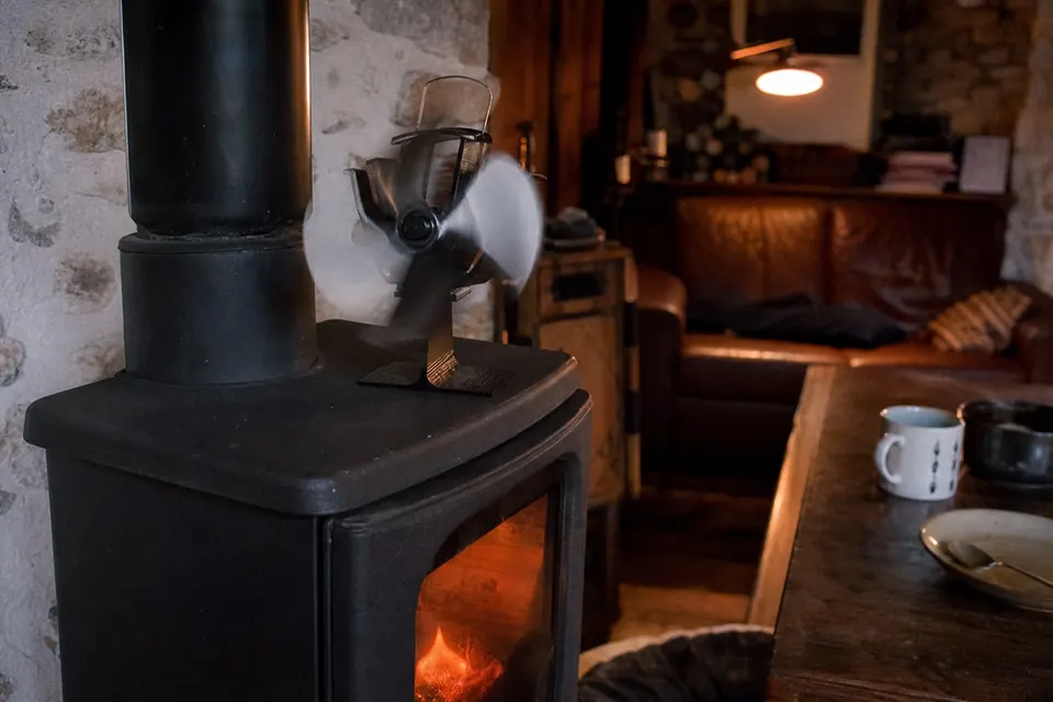 Petit ventilateur de poêle qui tourne sur le dessus d'un poêle à bois noir
