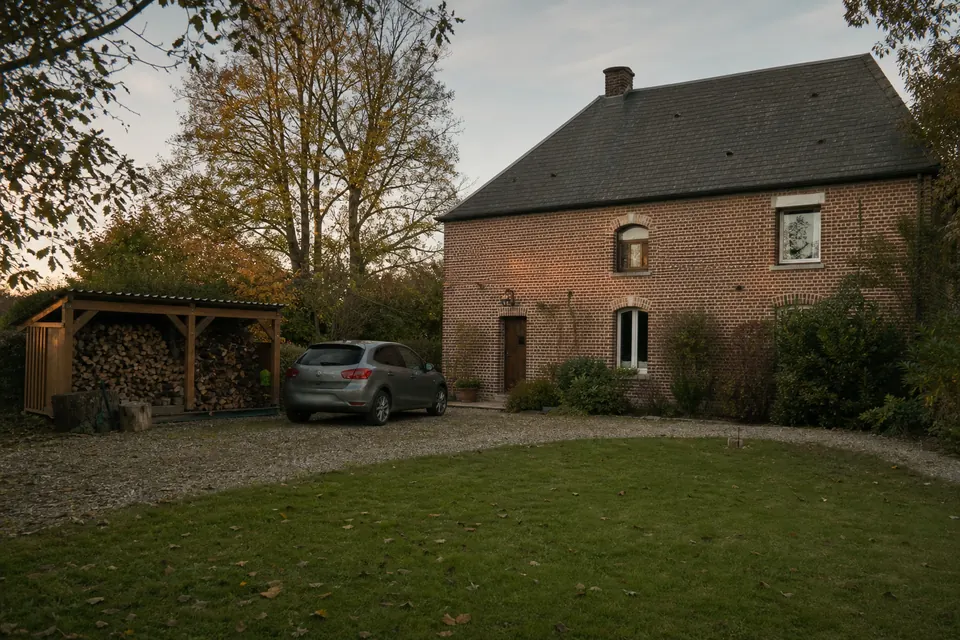 Maison en briques avec un abri à bois sur le côté dans la campagne de l'Eure