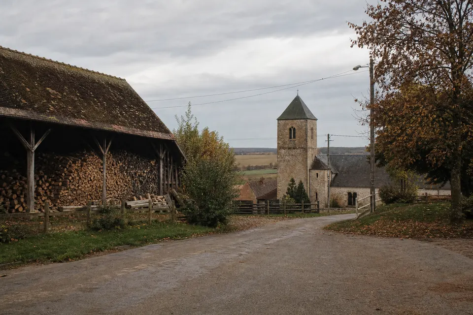 Village du plateau avec son église en pierre et une grange remplie de bûches